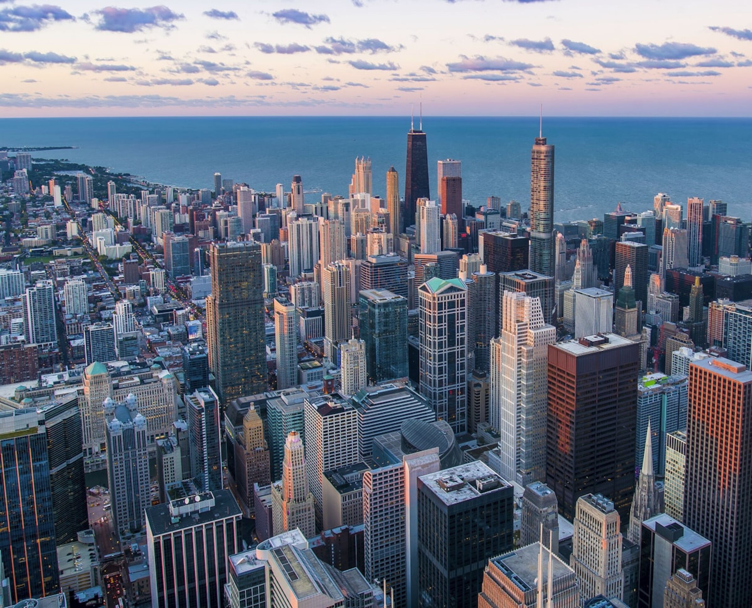 A city skyline at dusk, glass towers catching the last crimson light